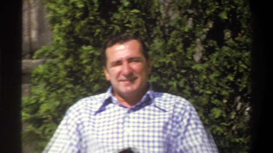 A closer home-movie view shows the smiling man in a checkered shirt against leafy hedges, with soft 8mm color and focus.