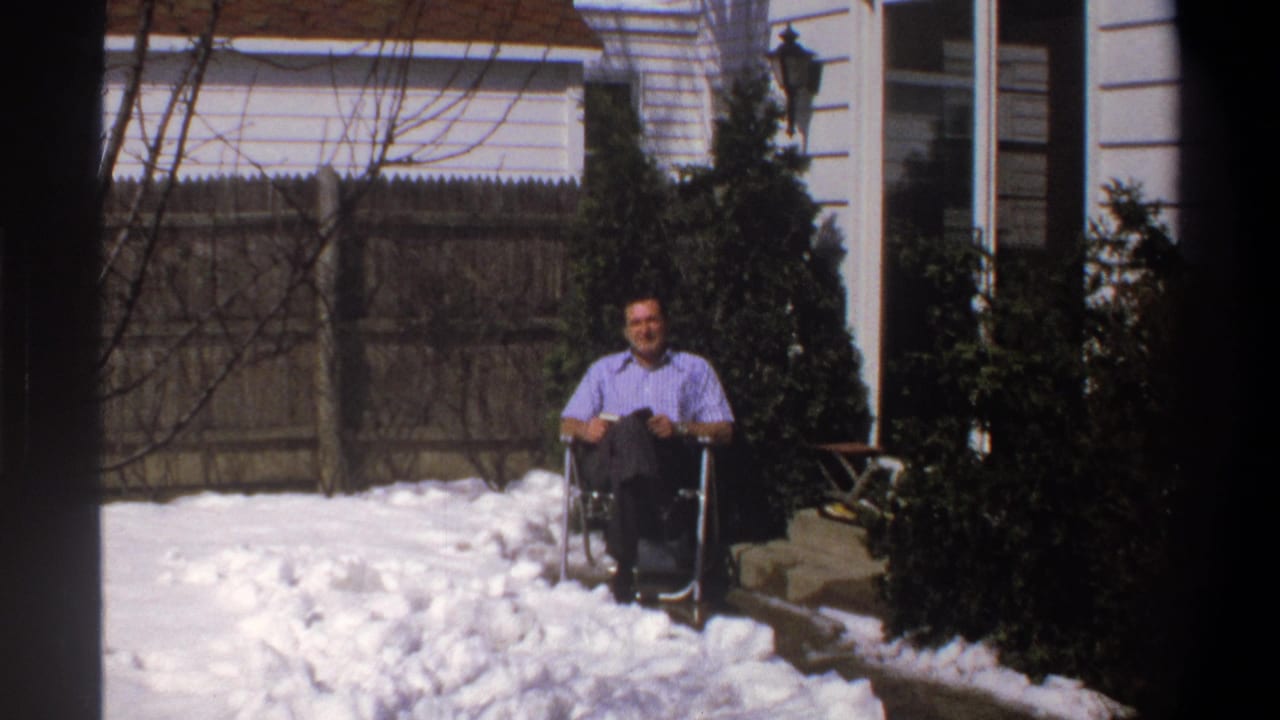 1969 home-movie frame from the supplied Cape Town clip showing a man in a wheelchair facing the camera in a snowy yard.
