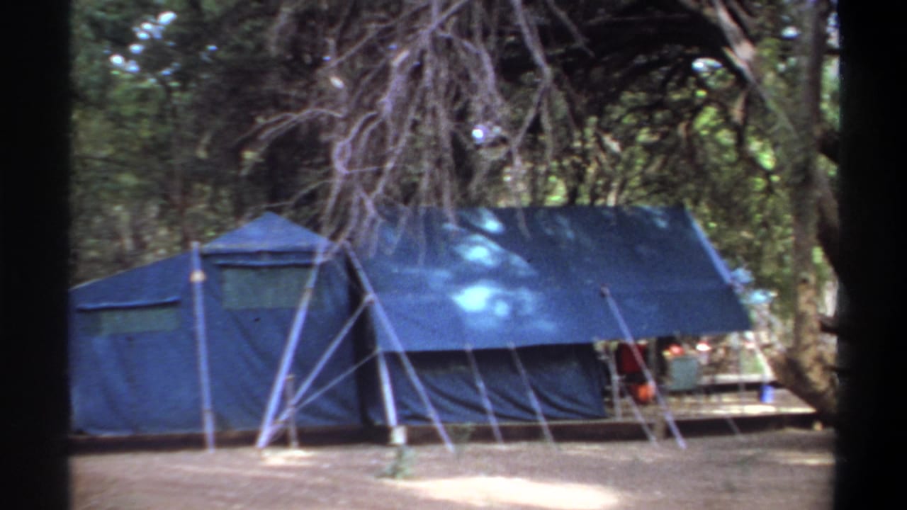 Blue canvas camp tent in a wooded Khartoum setting, filmed in soft 8mm color in 1969.
