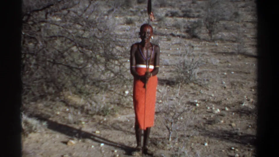1969 Khartoum, Sudan 8mm frame showing a man in an orange wrap facing the camera in dry scrub terrain.