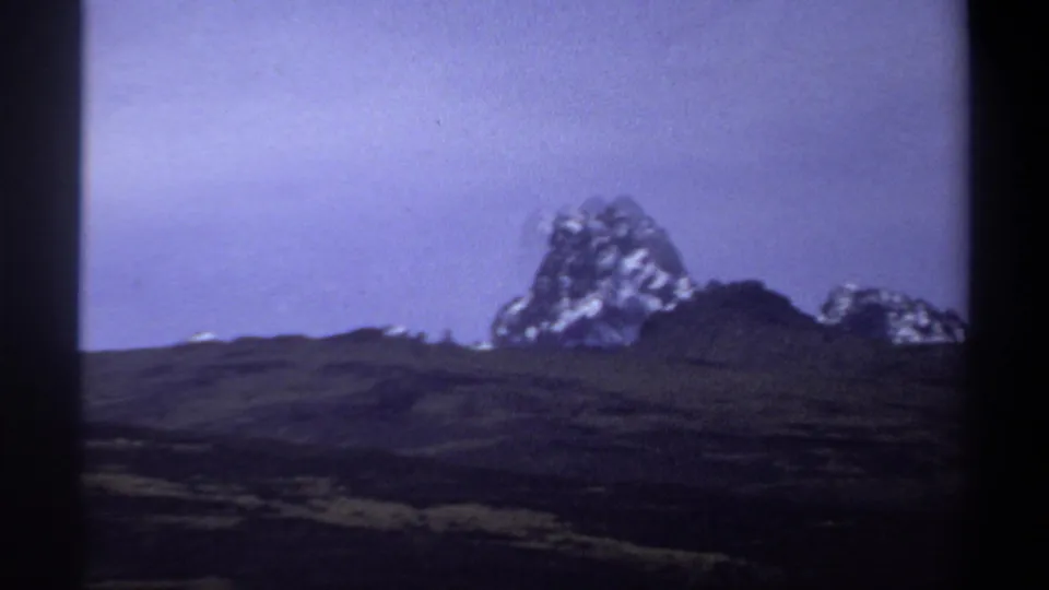 1969 8mm frame with a distant mountain near the horizon, rolling hills below, and visible dark gate borders from the film scan.