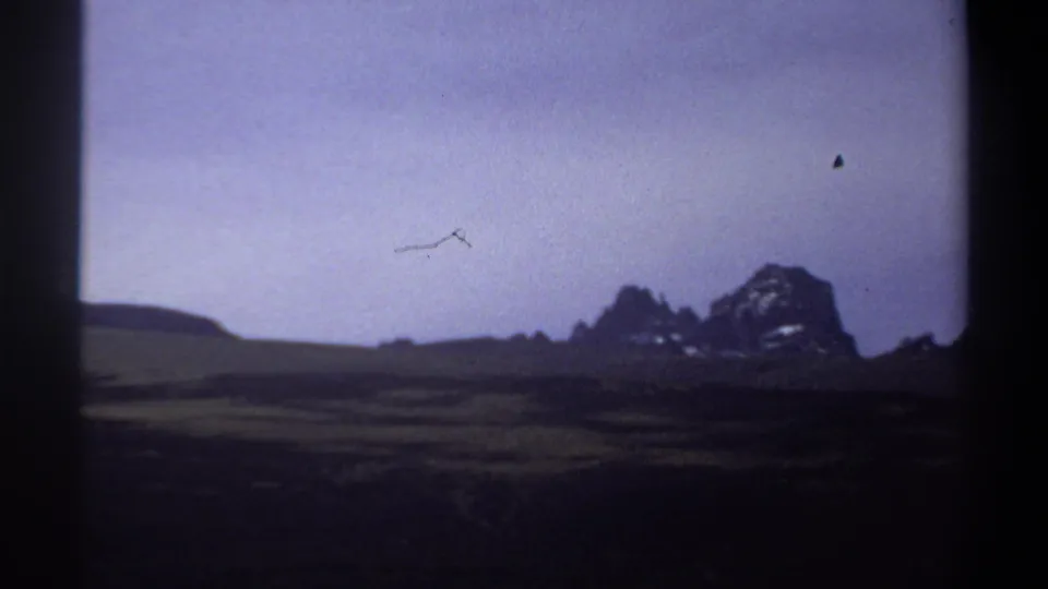 1969 Sudan home-movie view of open plains and rocky hills, with visible dust or scratch marks in the sky area.