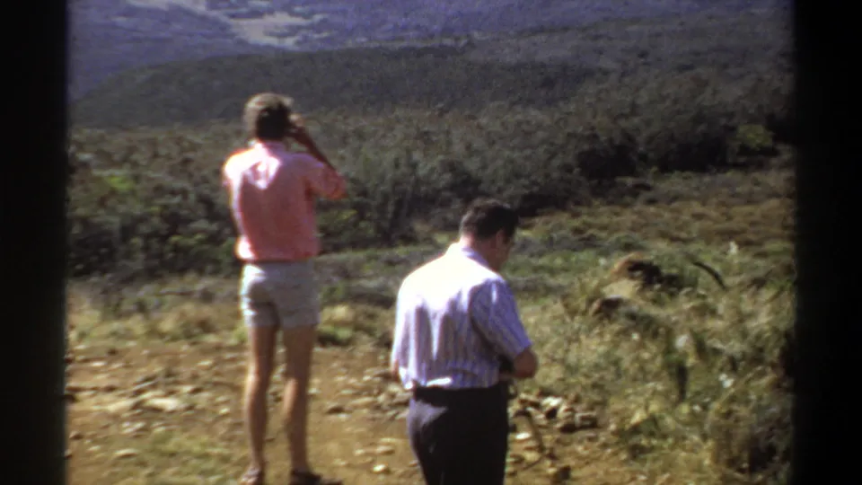 In metadata-listed Khartoum, Sudan, 1969, two adults pause in scrubby terrain with hills in the distance.