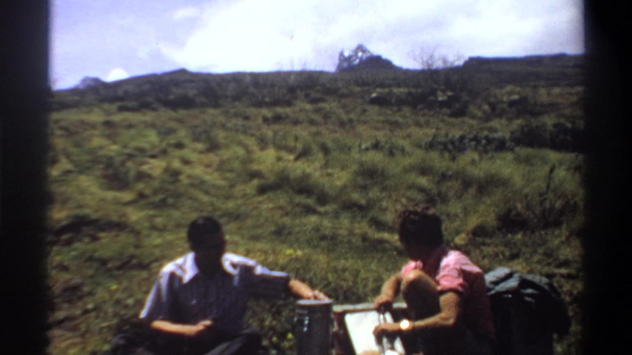 In 1969 Khartoum, Sudan footage, two men sit on a grassy hillside near bottles, a pale box, and a dark bag.