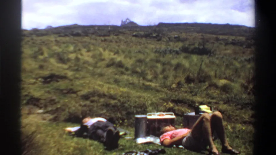 The 1969 Khartoum picnic footage shows two adults resting near a box, containers, and scattered items in tall grass.