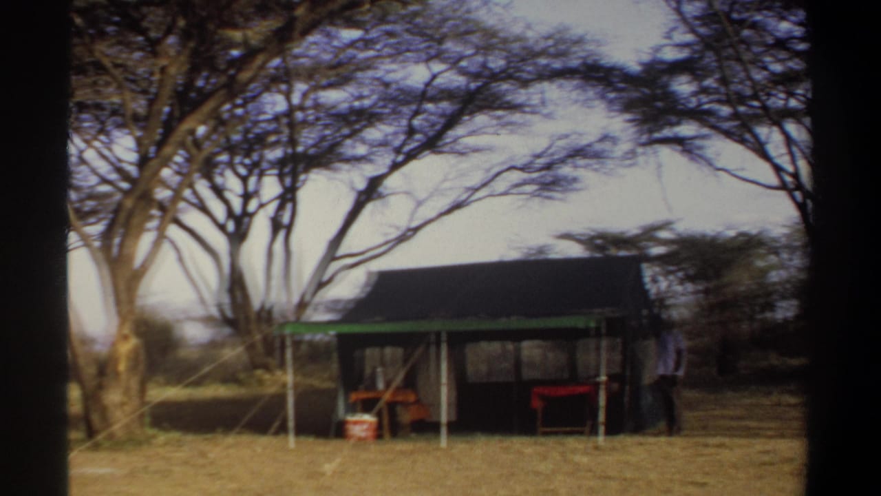 1969 Khartoum, Sudan home-movie frame showing a canvas camp tent, green awning, sparse trees and simple outdoor furniture.