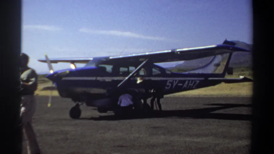 1969 Khartoum frame showing the blue and white aircraft marked 5V-AHZ, with two men working near the door and landing gear.