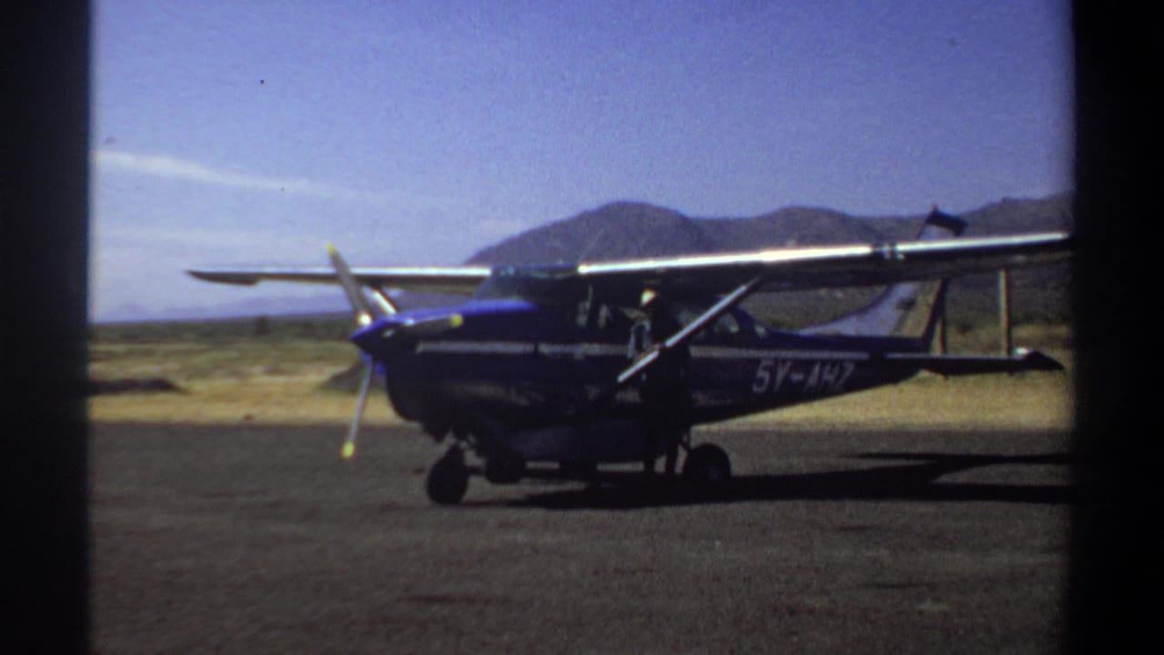 Blue and white airplane seen side-on on an airfield runway.