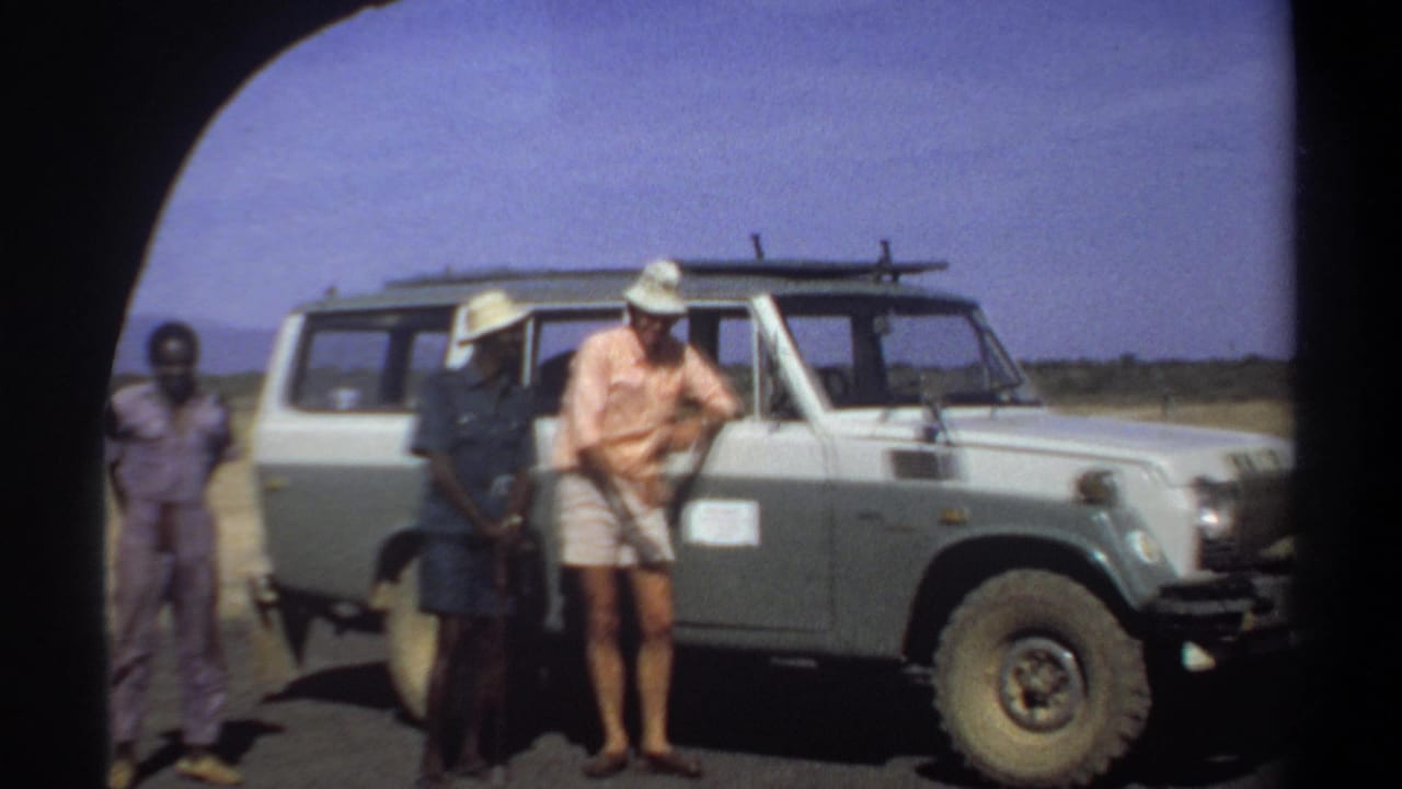 In Khartoum, Sudan in 1969, three men stand near a pale Land Cruiser in bright sun, with the visiting man leaning by the front door.