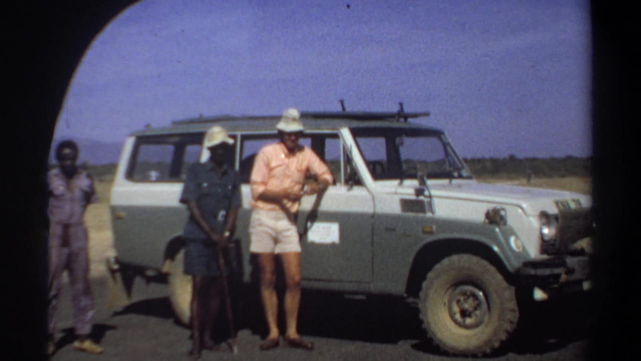 A man in shorts stands with two local men beside a Land Cruiser.