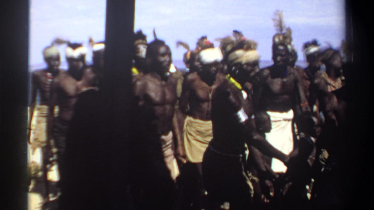 Group members pass near dark vertical shadows, wearing headbands, cloth wraps, and armbands.