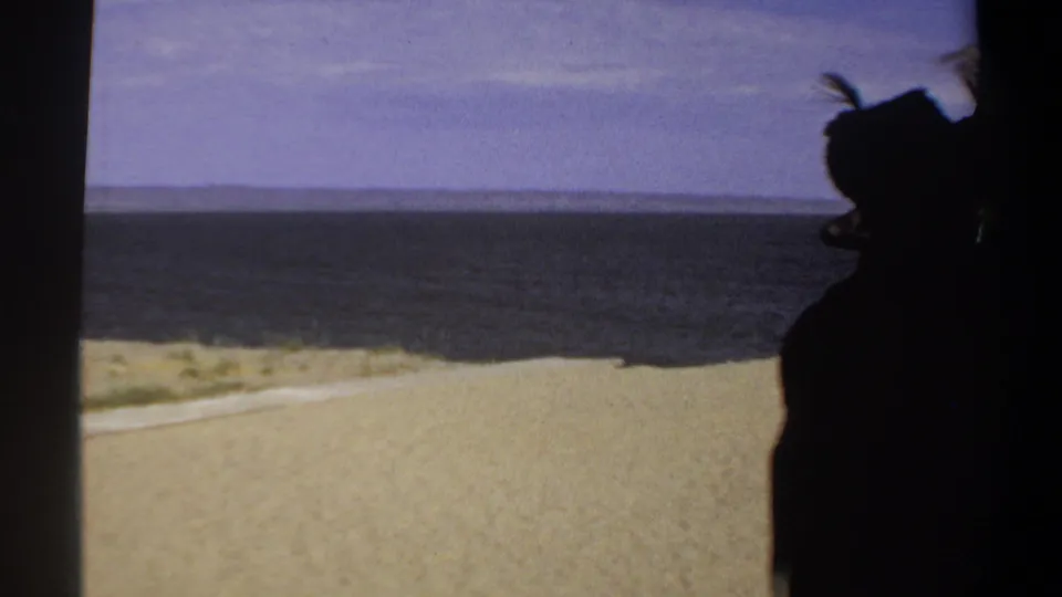 A strongly silhouetted person appears at the edge of a 1969 Sudan beach scene, with sand, open water, and horizon visible beyond.