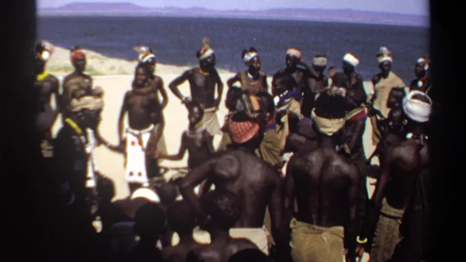 1969 Sudan 8mm frame showing a central participant within a circle of men during an outdoor dance or ceremony.