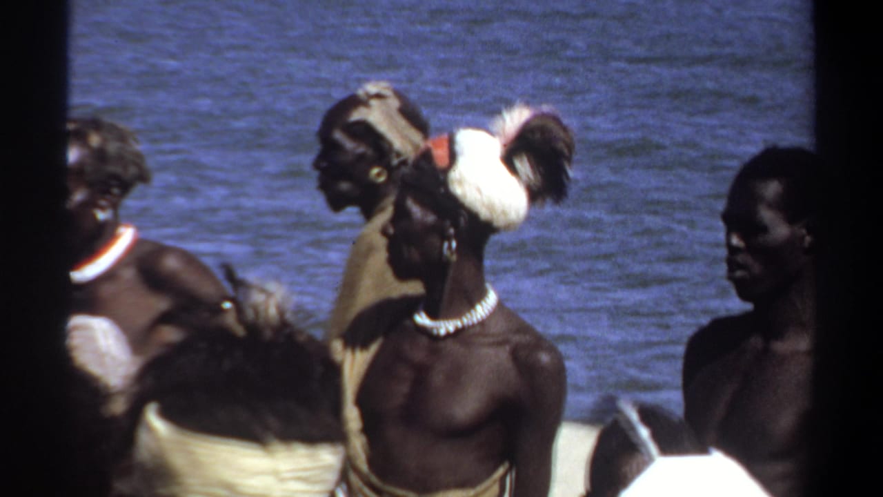 Several adult men stand by water, with one figure partly blocked by a dark vertical edge.