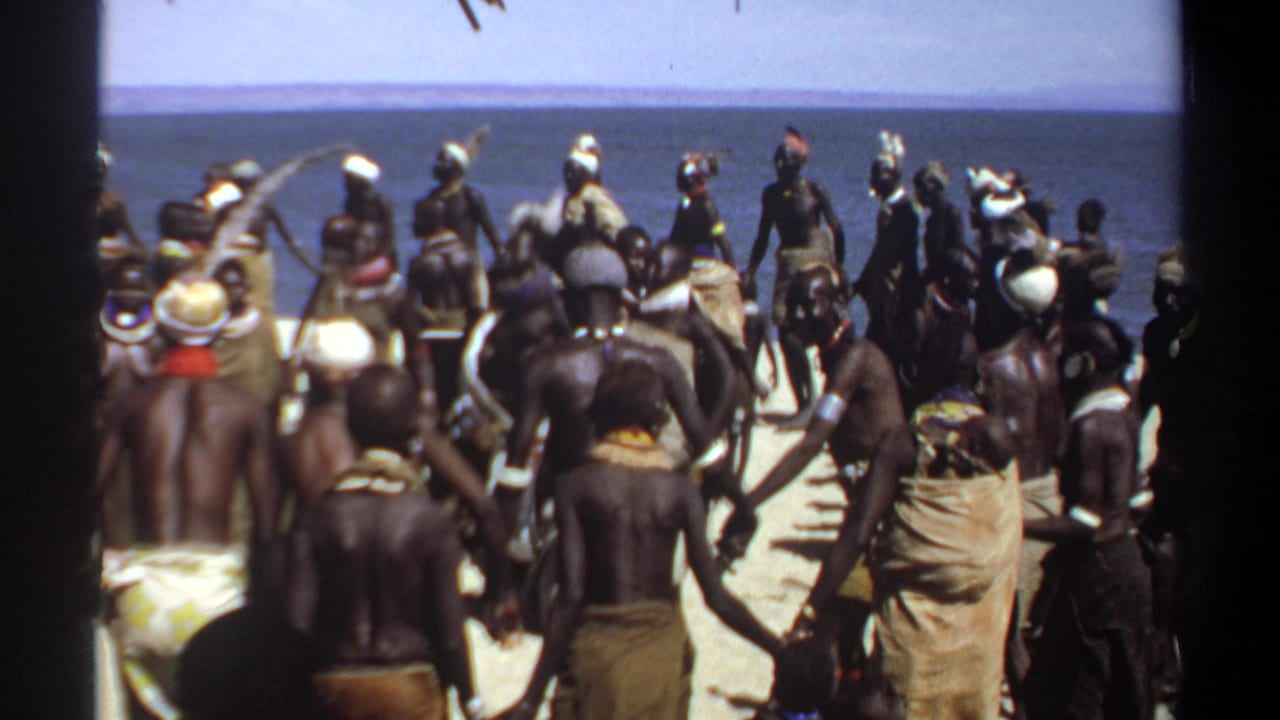 1969 Khartoum, Sudan home-movie frame showing a crowd in wraps and head coverings gathered near the water's edge.