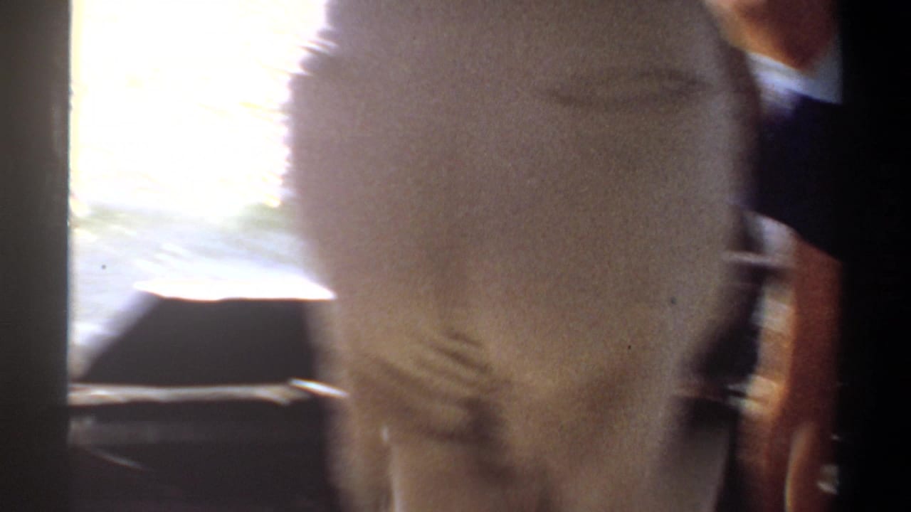 1969 Khartoum home-movie frame showing a blurred passenger beside the boat edge as sunlight reflects off the water.