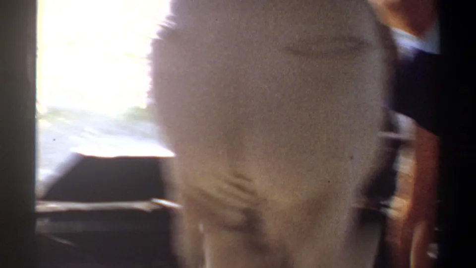 1969 Khartoum home-movie frame showing a blurred passenger beside the boat edge as sunlight reflects off the water.