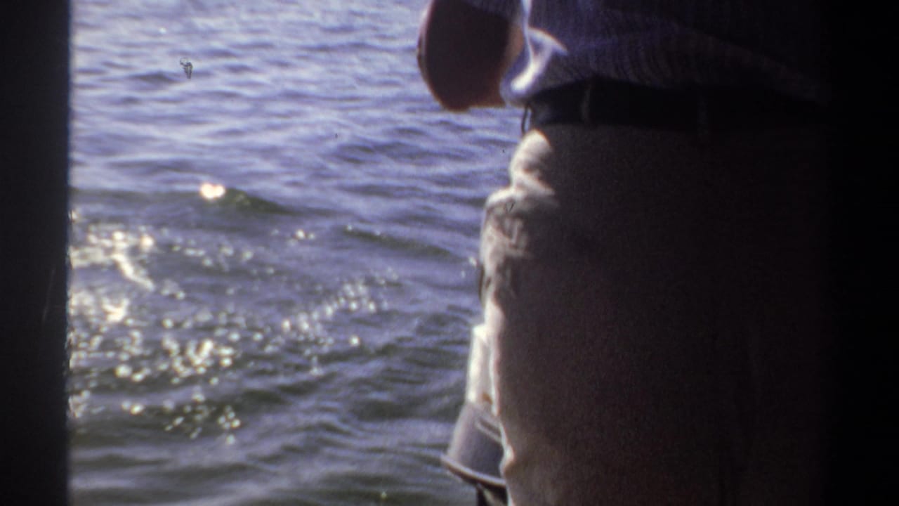 Partial view of passengers on a boat beside rippling water.