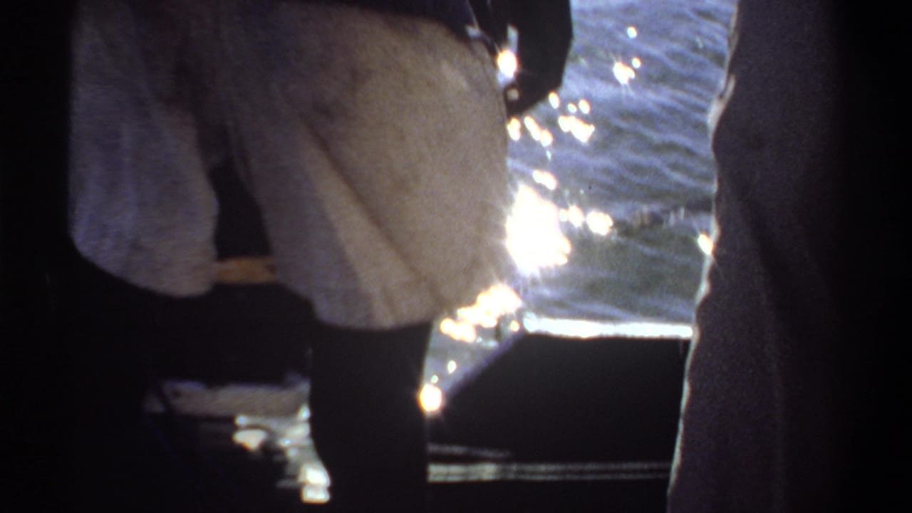 Person in white shorts steps near the edge of a boat with water in the background.