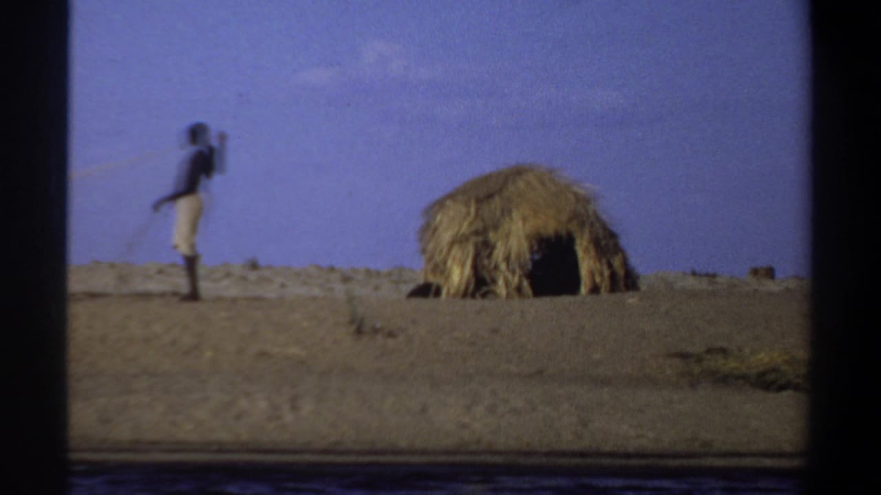 Distant man near a thatched hut on flat dry terrain.