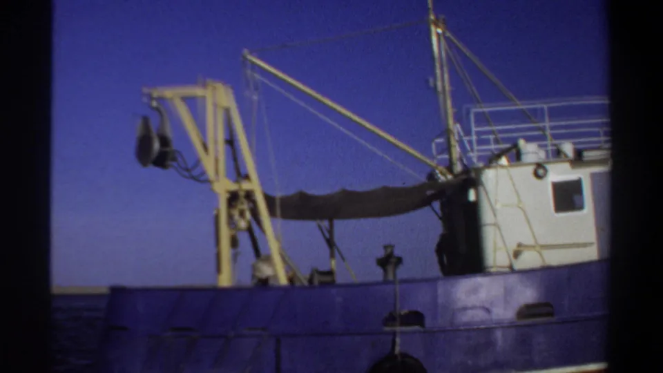 1969 Sudan 8mm frame of boat deck equipment, rigging, and the edge of a white cabin above a blue hull.