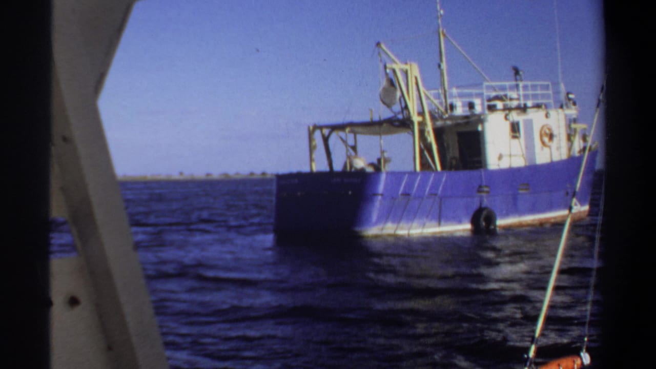 1969 Sudan 8mm frame showing a blue and white boat on calm water, with a nearby vessel edge visible in the foreground.