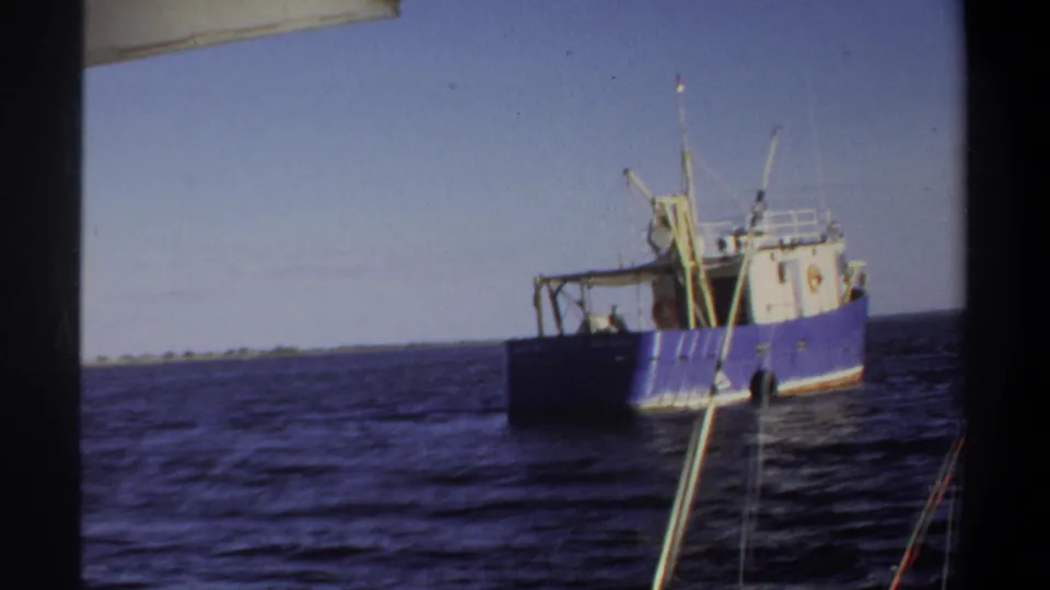 1969 8mm Sudan footage showing a blue and white fishing vessel on dark open water, seen from another boat.