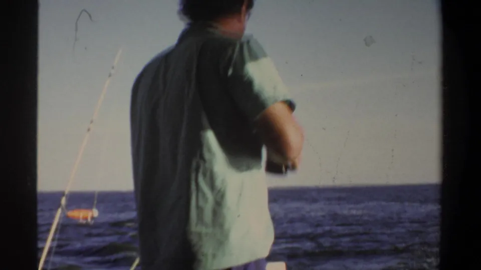 Adult man in a light green shirt stands on a boat, seen from behind against open water in 1969 home-movie footage from Sudan metadata.
