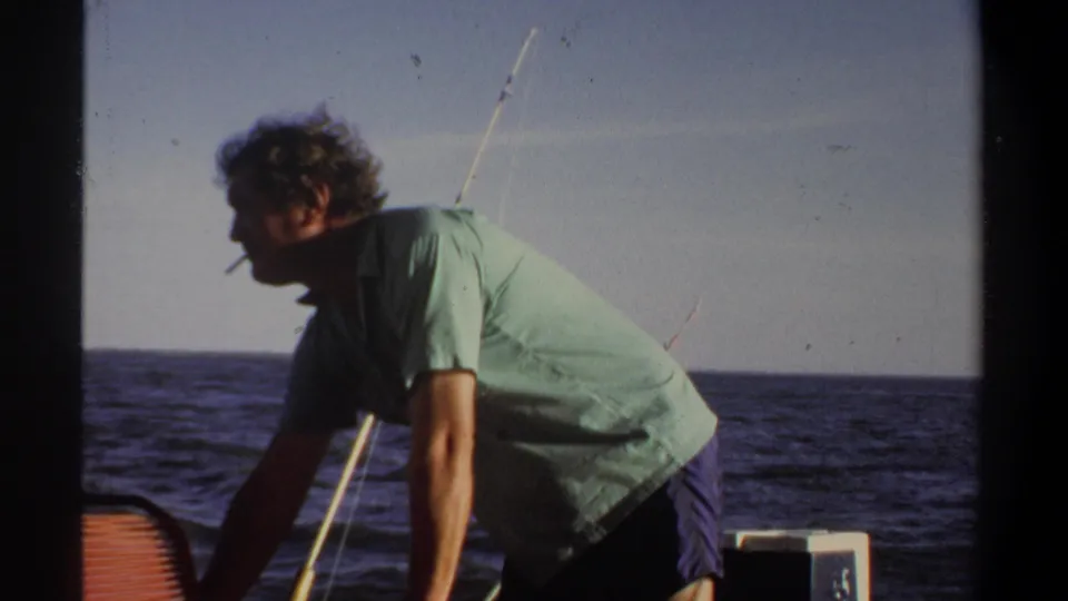 In the final frame, the man smokes while leaning forward on a boat, with open water and fishing gear visible in Khartoum footage from 1969.