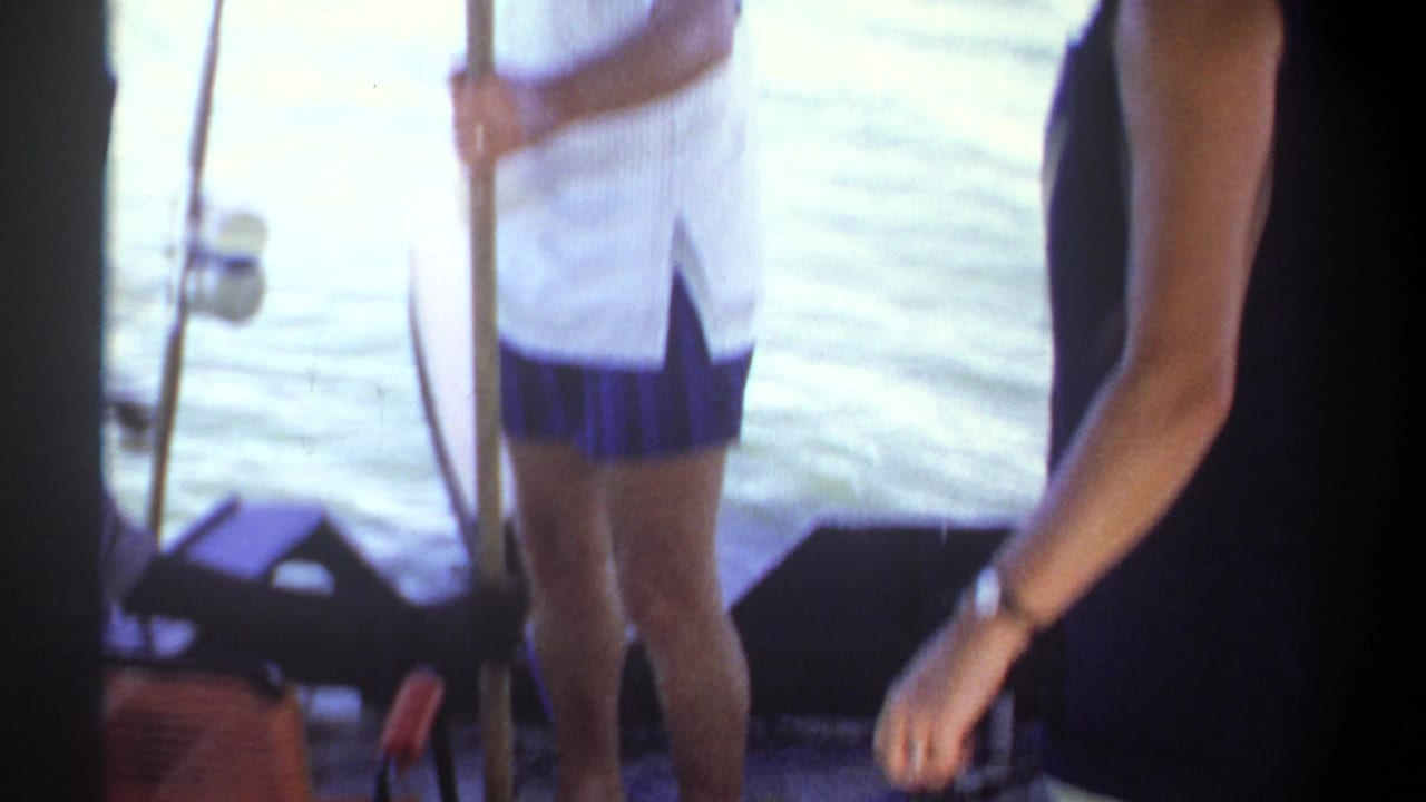 1969 Sudan home-movie frame showing adults aboard a small boat near water, with close handheld framing and film borders.