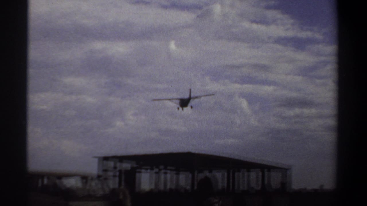 Small aircraft appears above a low open-sided airport shelter in Khartoum, Sudan, in 1969 footage.