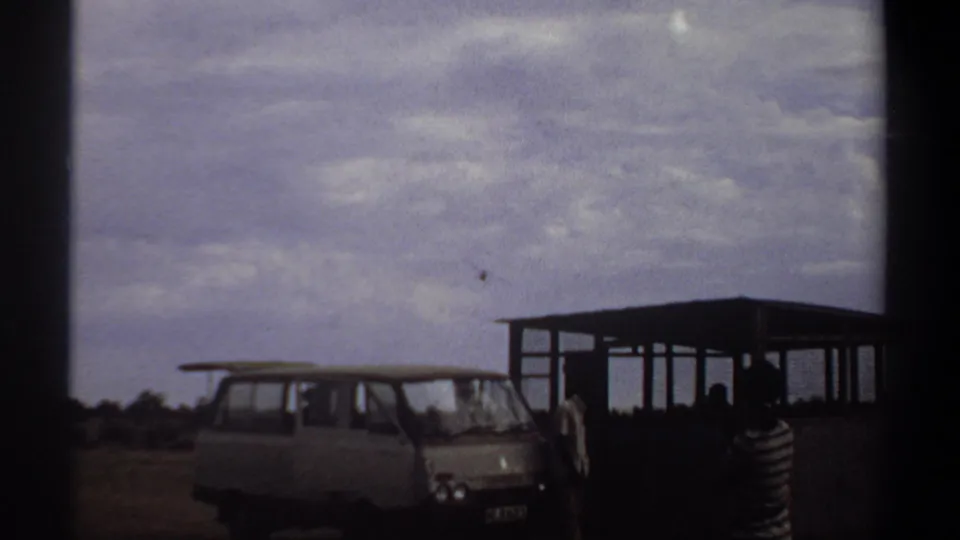 1969 Khartoum footage shows the aircraft higher in the sky while onlookers remain beside the van and open shelter.