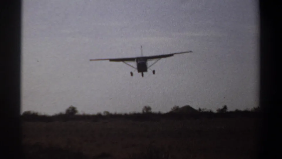 A small airplane nears the ground with gear lowered in 1969 Khartoum, Sudan, 8mm footage.
