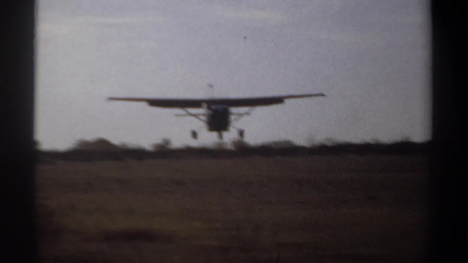 Single-engine airplane approaches touchdown over a rural runway in Khartoum, Sudan, archival 8mm footage from 1969.