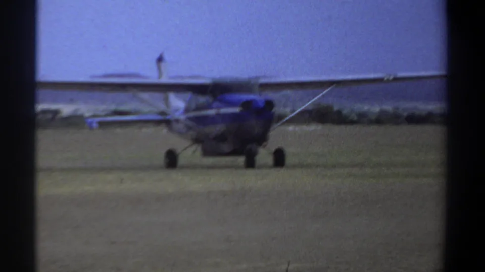 Home-movie still from Khartoum in 1969 showing the small propeller plane turning or passing on a grass airfield.