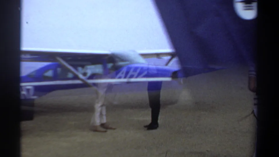 Three people stand near the tail of the blue and silver aircraft in the 1969 Khartoum home-movie footage.