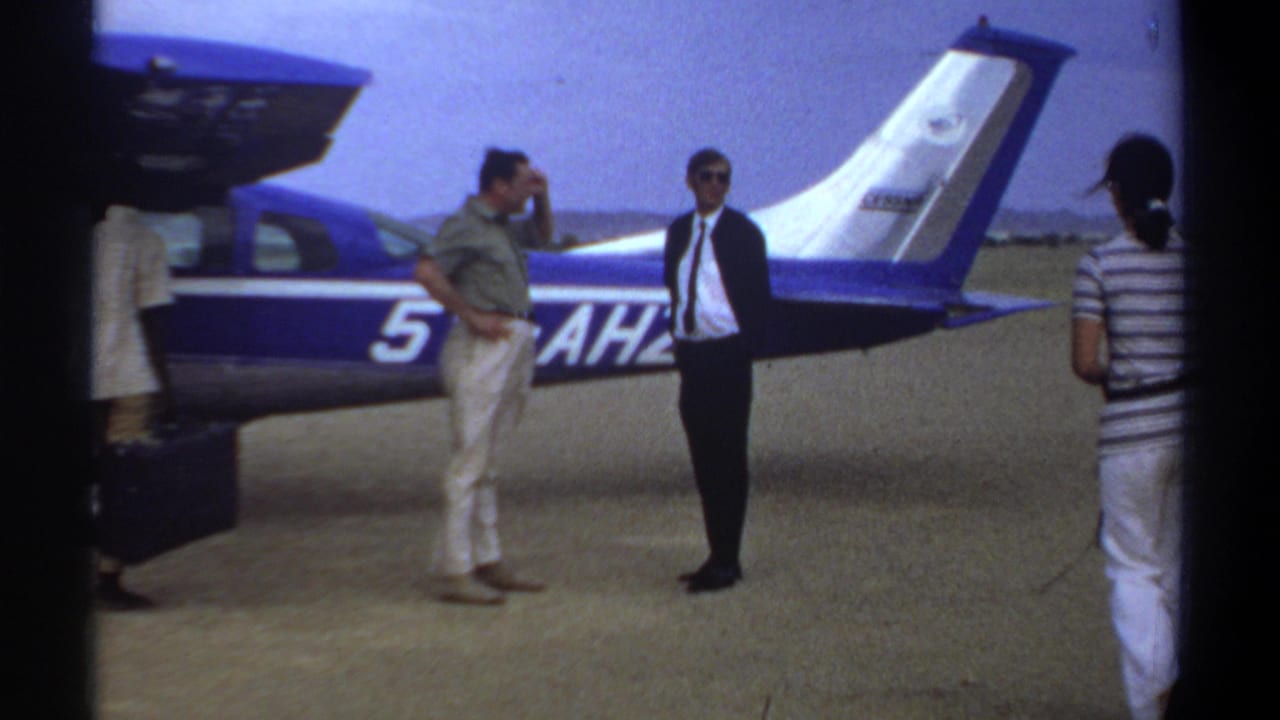 Khartoum, Sudan, 1969 home-movie frame showing adults near an open blue-and-white light aircraft before boarding.