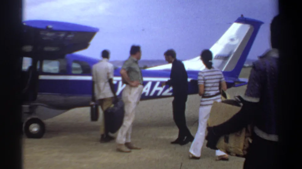 Khartoum, Sudan, 1969 frame showing passengers, luggage, and crew activity beside a blue-and-white plane.