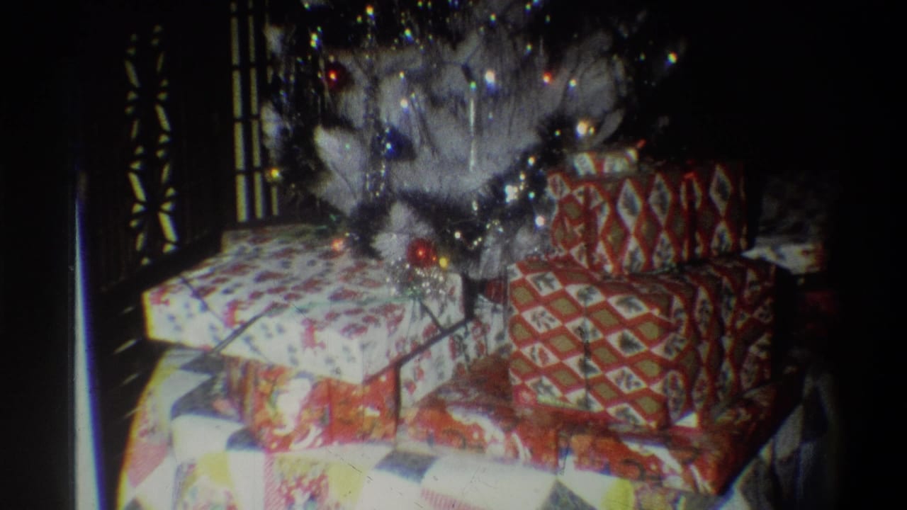 A dim 1973 Troy holiday interior shows patterned presents arranged beneath a white artificial Christmas tree.