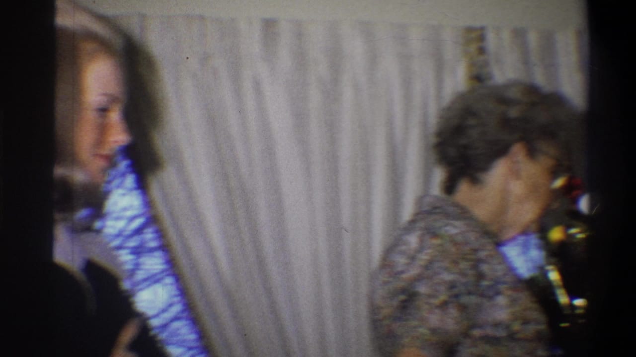 Younger woman at left and older woman near a small Christmas tree indoors.