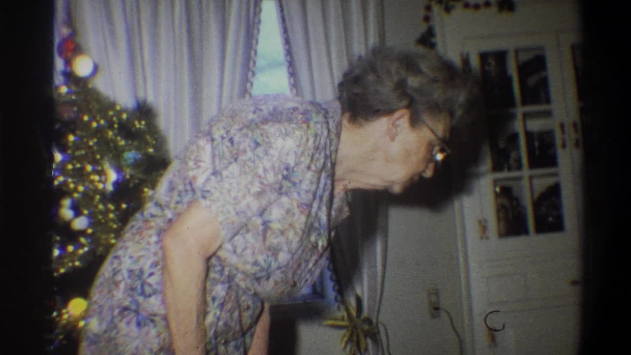 1973 Troy, New York frame with an elderly woman leaning down near ornaments, white curtains and interior doors.