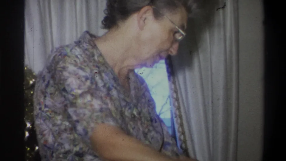 1973 Troy, New York frame with a closer view of the woman in glasses near the curtained window and Christmas tree edge.