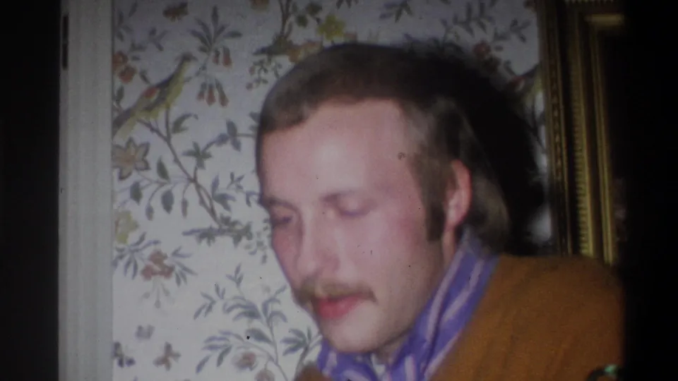 The man looks down in the final frame, with a gold-toned wall frame and floral wallpaper visible in the private interior.