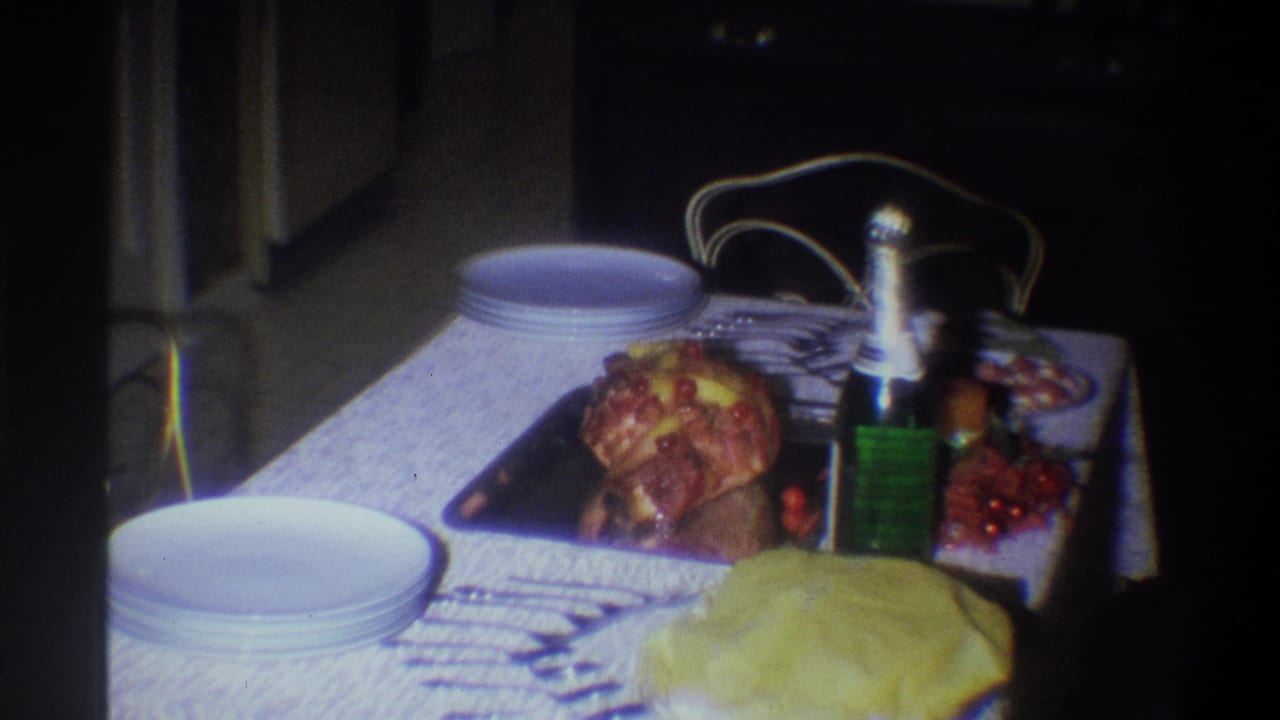 A dining table in a private Troy, New York interior holds stacked white plates, roasted chicken, a green wine bottle, and serving dishes.