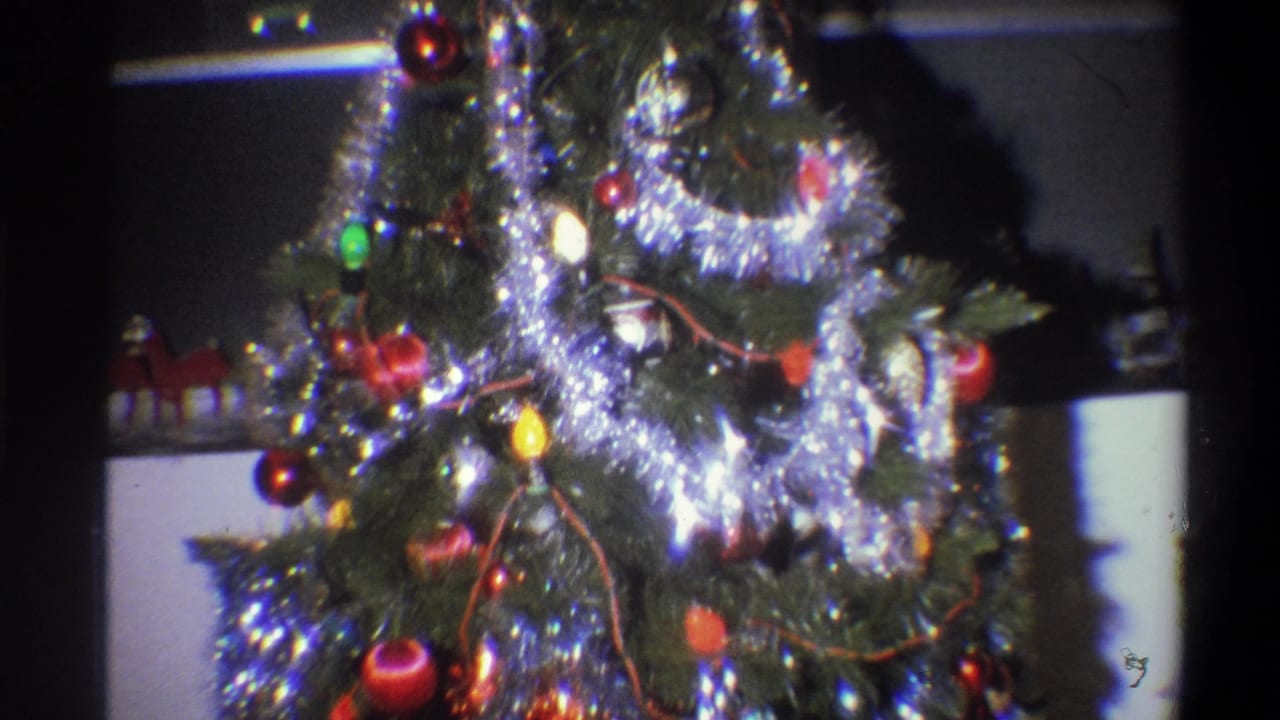 Close view of a decorated Christmas tree with silver tinsel, red ornaments, and colored lights.