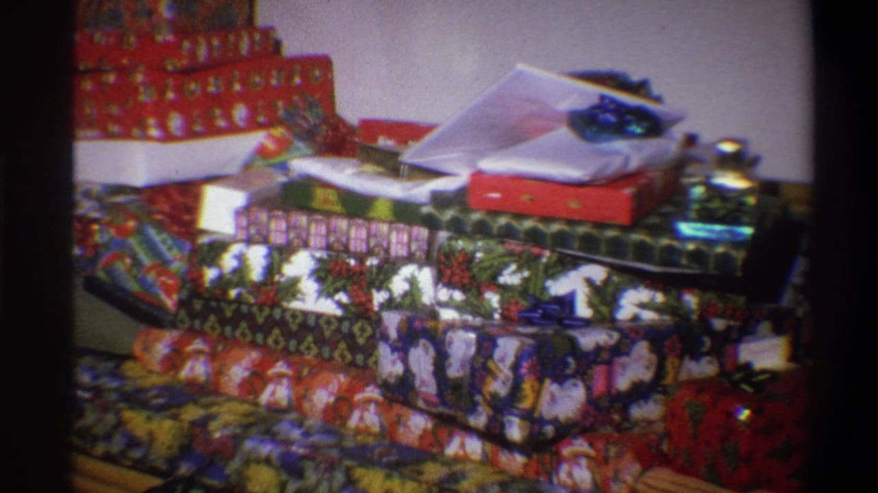 A 1973 home-movie view from Troy, New York shows stacked Christmas gifts in colorful wrapping, filmed close-up on 8mm.