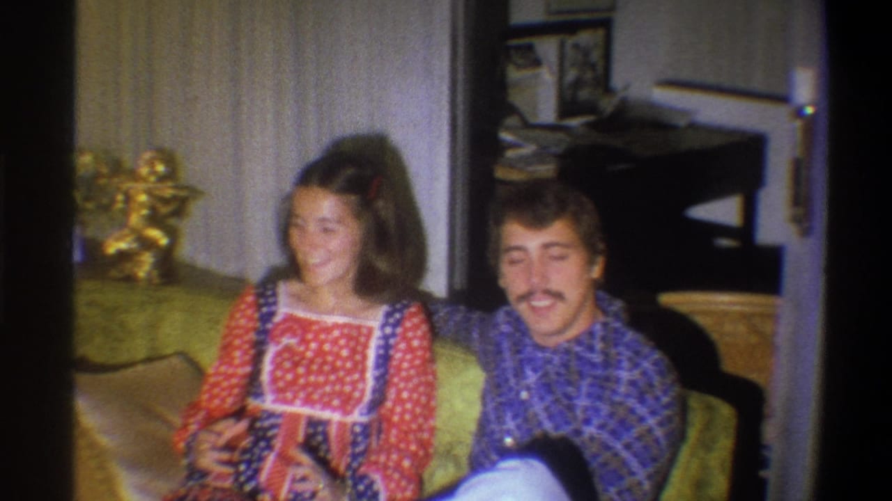 In Troy, New York, 1973 home-movie footage, a young couple sits on a green couch in a patterned 1970s living room.