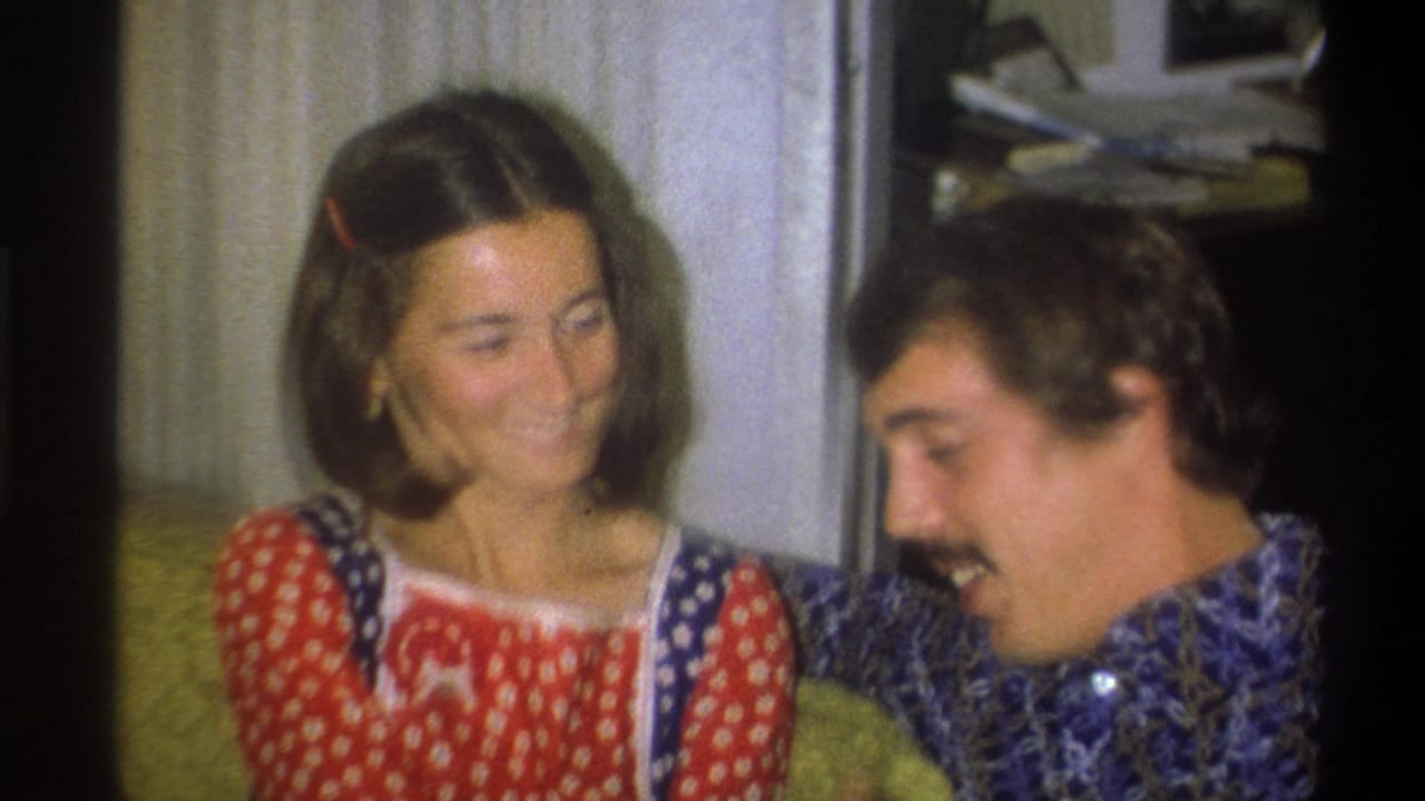 In 1973 Troy, New York home-movie footage, a young woman in a red polka-dot dress smiles beside a mustached man in a blue patterned shirt.