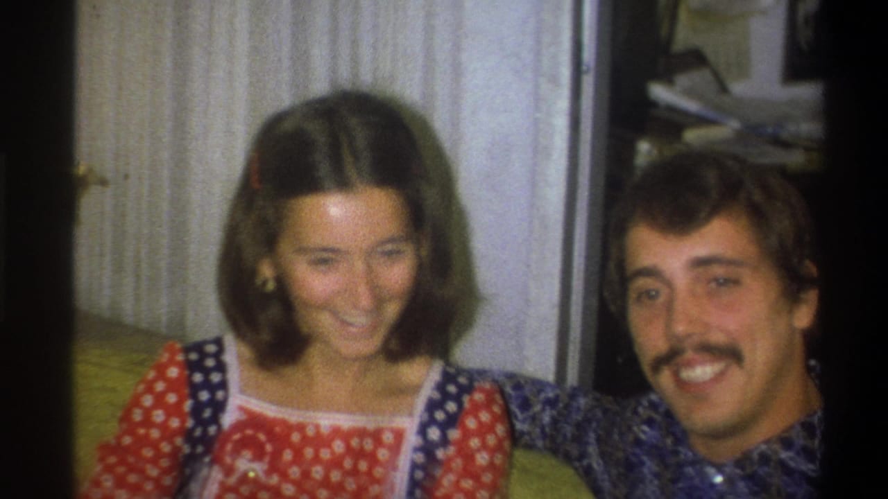 A 1973 Troy, New York 8mm frame shows the woman looking down with a smile as the man turns toward the camera.