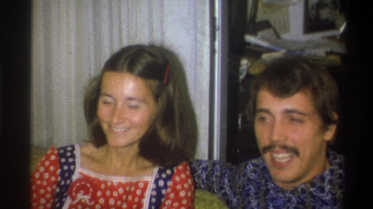In Troy, New York 1973 home-movie footage, a young woman in a red and blue patterned dress smiles beside a mustached young man in a blue shirt.